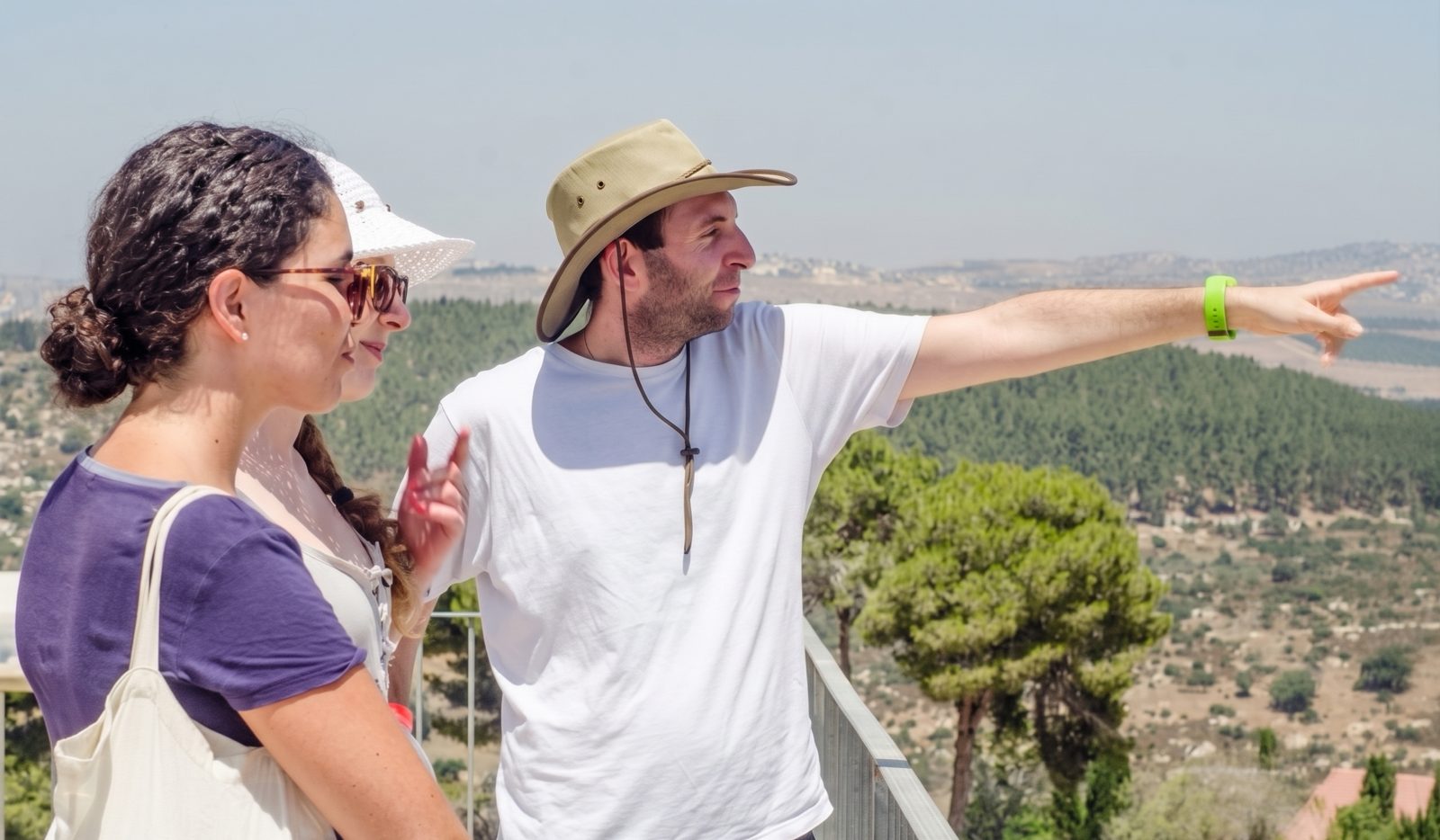 Samuel Green, a licensed Israeli tour guide, pointing out the view to two visitors at a hilltop overlook.