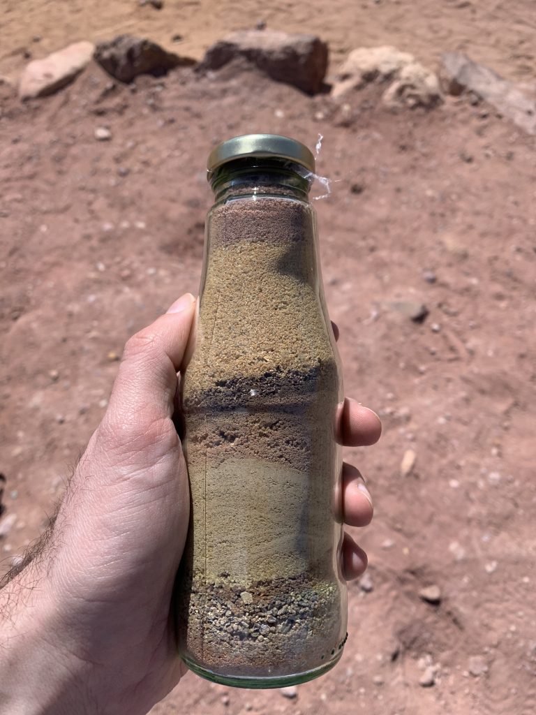 A glass bottle containing layers of different coloured sands collected in the Ramon Crater, Israel