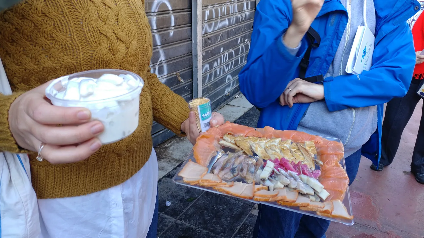 A group tasting cured and pickled fish at a Carmel Market counter