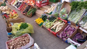 Boxes of vegetables, courgettes, aubergines, white radishes and greens, laid out at a Carmel Market produce stall