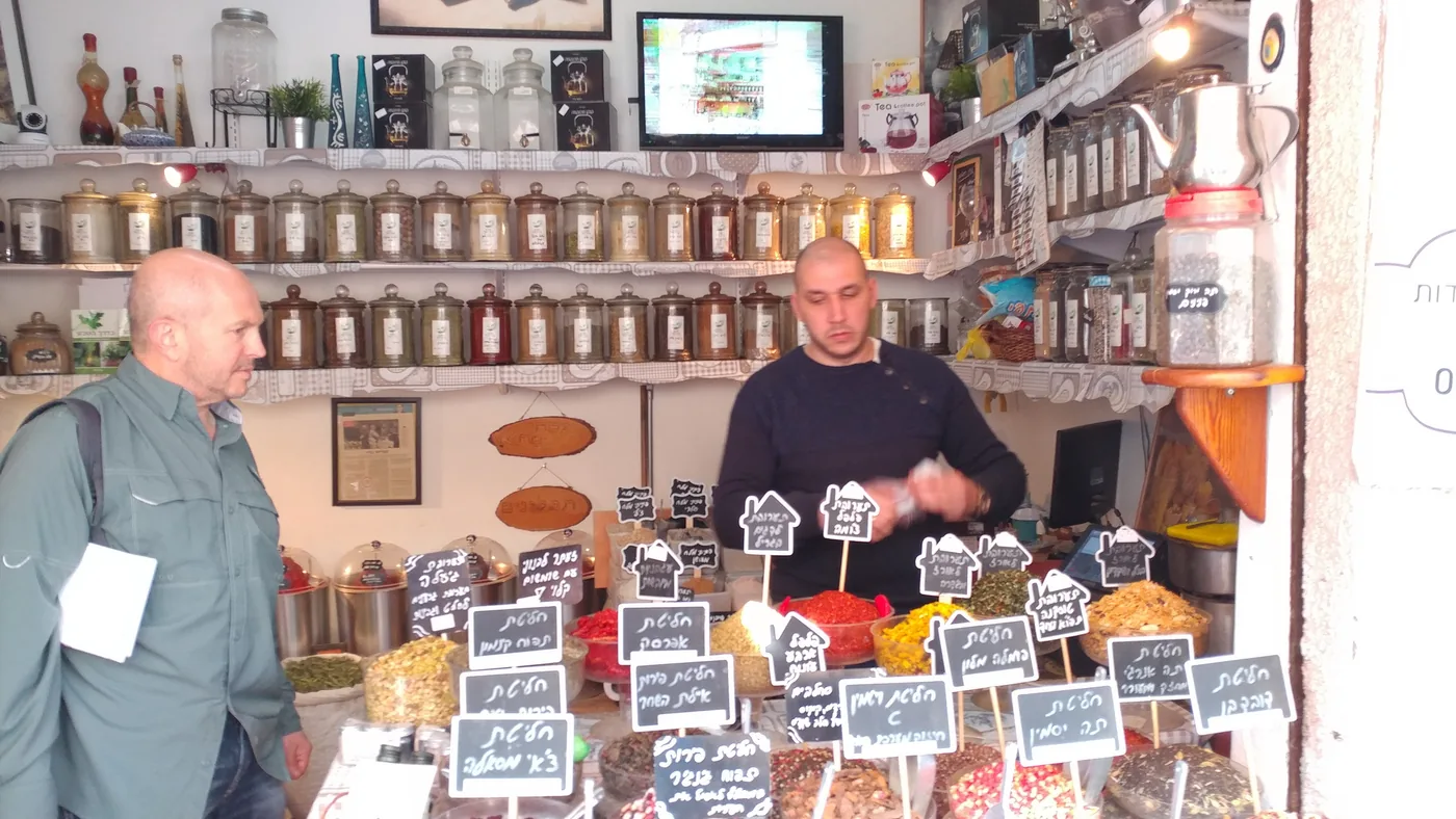 A guide holding out two scoops of different ground spices at a market spice stall