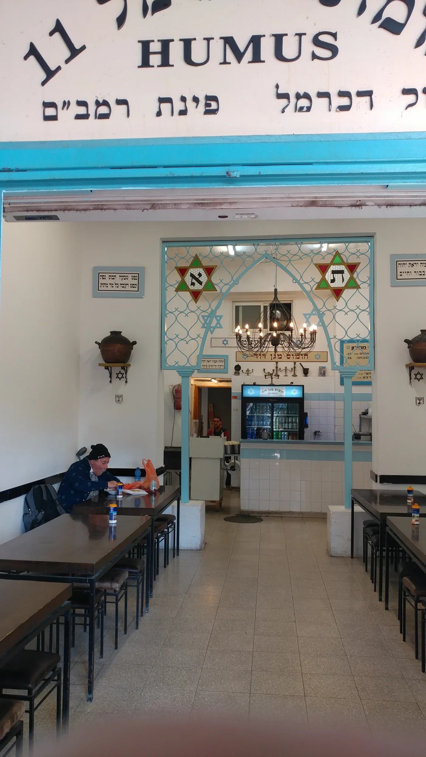 The interior of a hummus restaurant fitted out with stained glass, benches and religious fittings