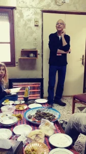 A host presenting a tray of home-cooked food to a group of visitors at a farm table