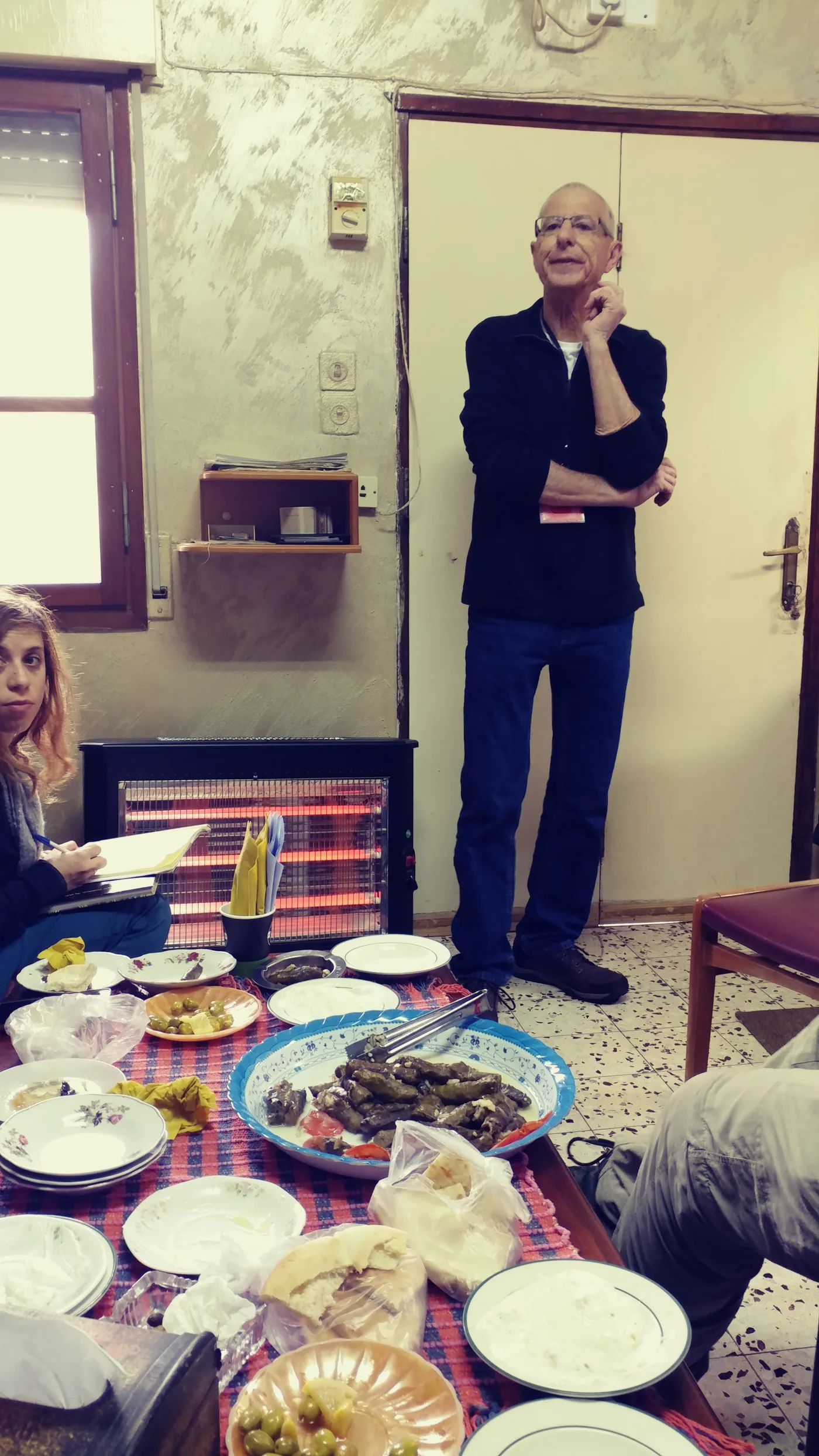 A host presenting a tray of home-cooked food to a group of visitors at a farm table