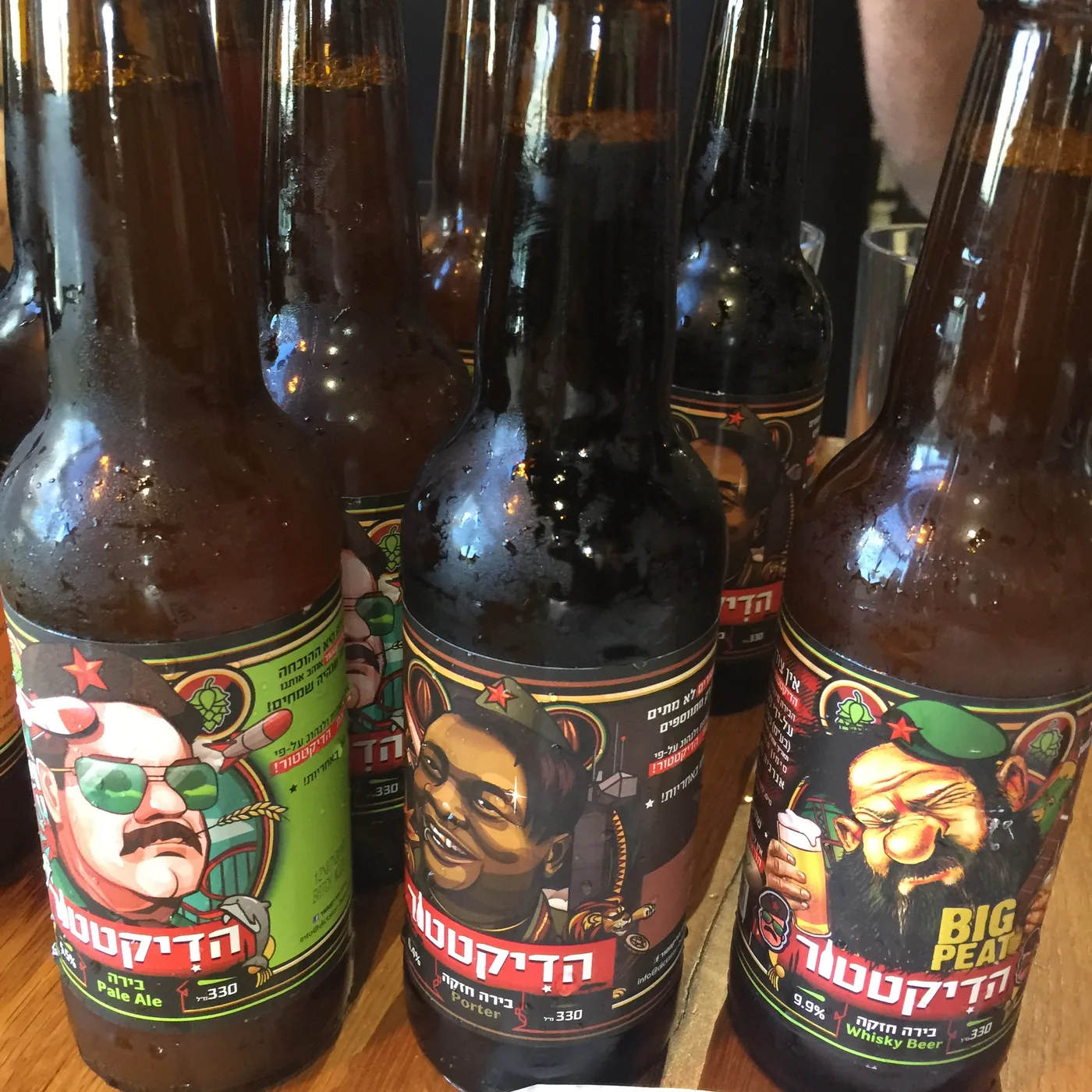 Bottles of Dictator Israeli craft beer lined up along a bar