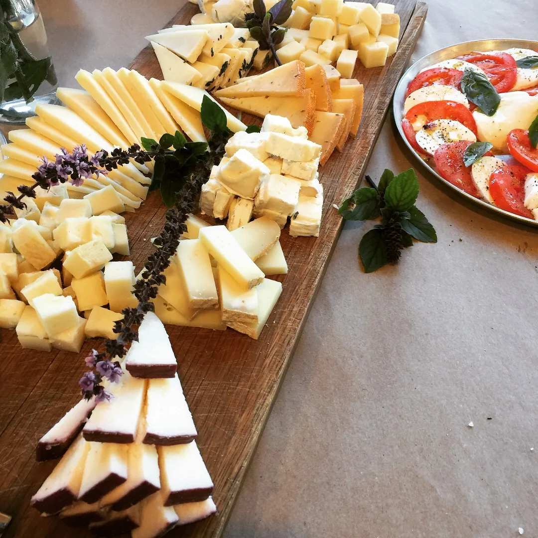A wooden board bearing several varieties of Israeli artisan cheese, yellow, white and aged