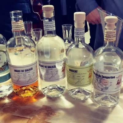 Bottles of Akko gin and Galilee eau de vie lined up on a wooden tasting table