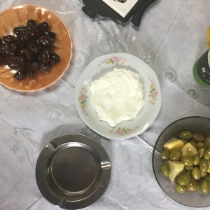 An overhead view of bowls of home-cured black and green olives and a plate of labneh on Madeleine's table