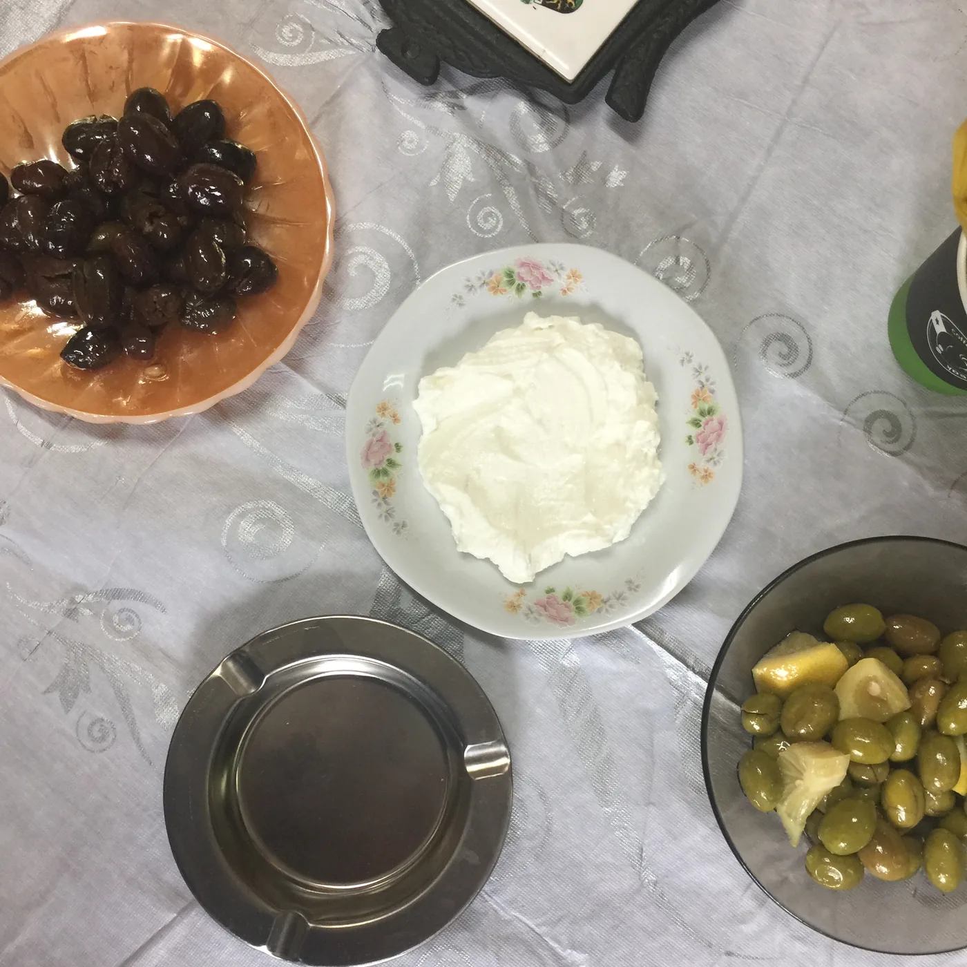 An overhead view of bowls of home-cured black and green olives and a plate of labneh on Madeleine’s table