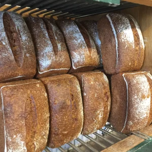 Rows of dark sourdough loaves cooling on wire racks at the Tishbi bakery