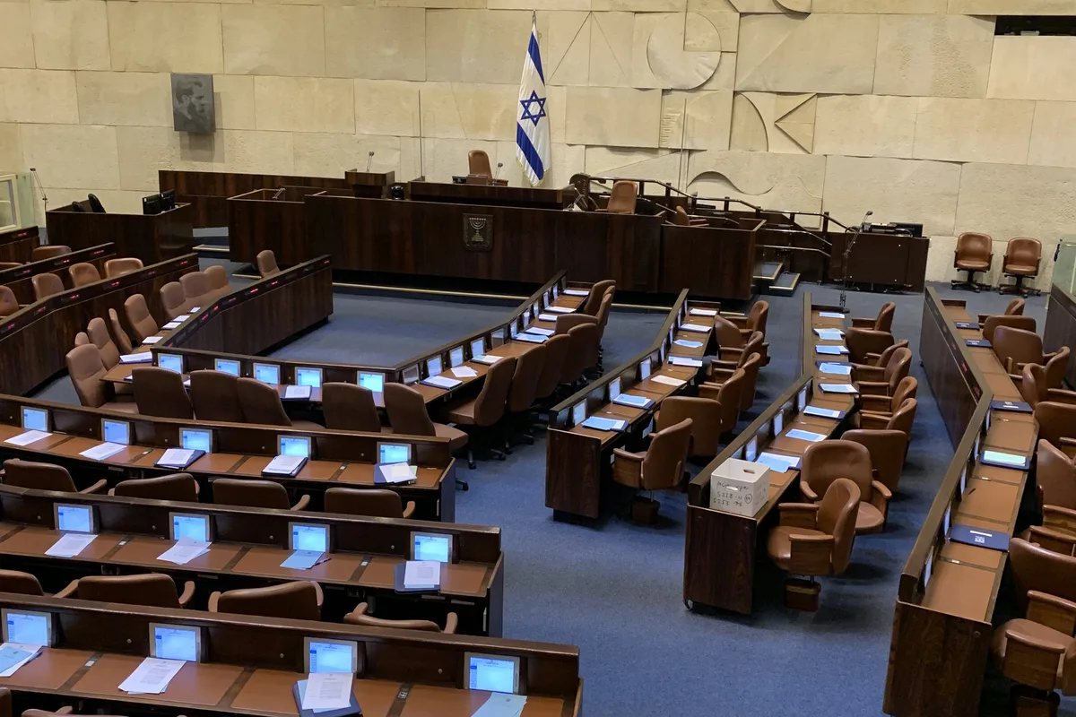 The Knesset plenum chamber in Jerusalem, with its horseshoe of members' seats and the Israeli flag.