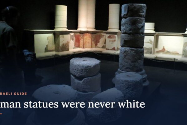 Painted wall panels and stone column sections from Masada in a museum gallery, with the title: Roman statues were never white