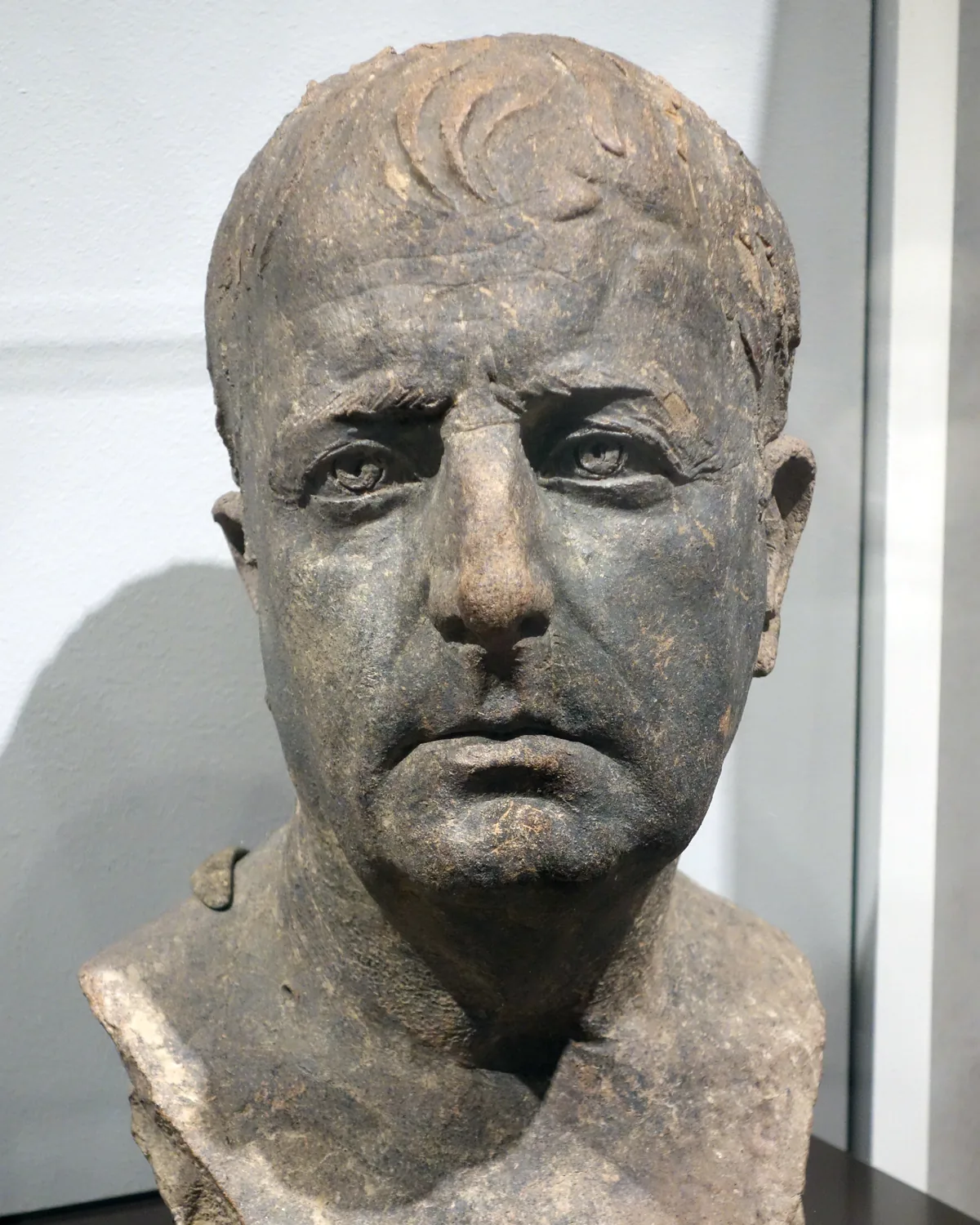 Terracotta portrait bust of an older Roman man with a deeply lined face and receding hair